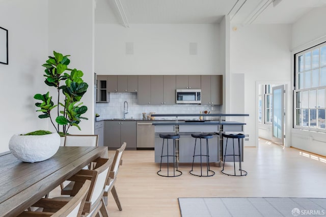 151 Alice B Toklas Pl Unit 610, San Francisco, CA 94109 - kitchen with gray cabinetry, appliances with stainless steel finishes, a towering ceiling, a sink, and decorative backsplash