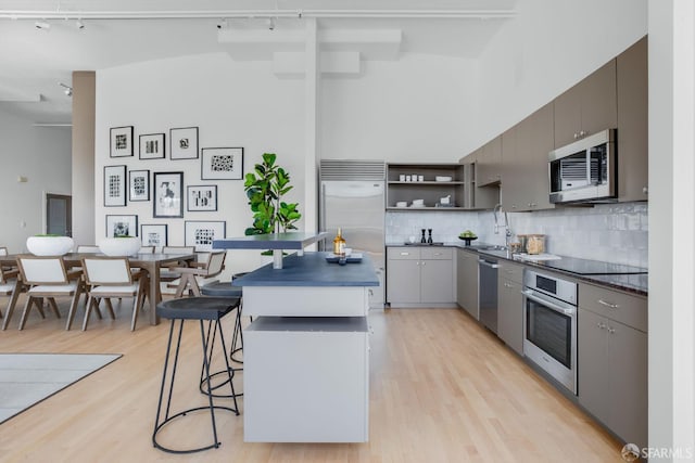 151 Alice B Toklas Pl Unit 610, San Francisco, CA 94109 - kitchen featuring stainless steel appliances, dark countertops, open shelves, track lighting, and a kitchen island