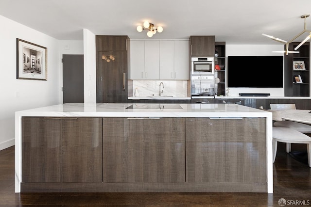 kitchen featuring sink, backsplash, white cabinets, and light stone counters