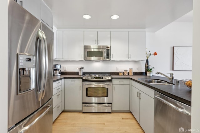 kitchen featuring white cabinets, sink, light wood-type flooring, kitchen peninsula, and stainless steel appliances