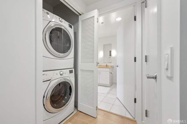 laundry area with light tile patterned flooring, sink, and stacked washer and dryer