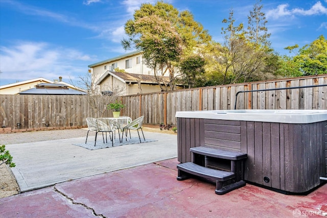 view of patio featuring outdoor dining space, a fenced backyard, and a hot tub