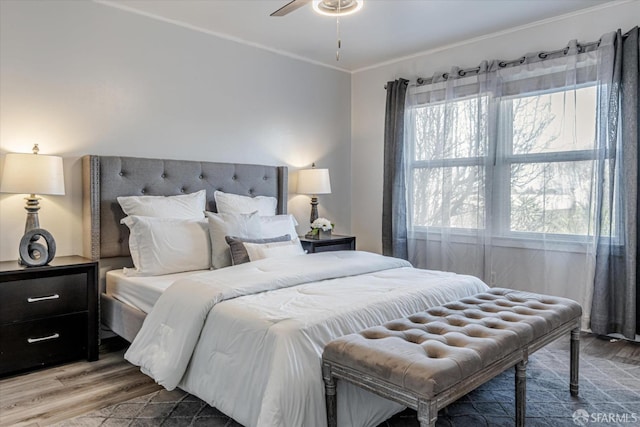 bedroom with ornamental molding and wood finished floors