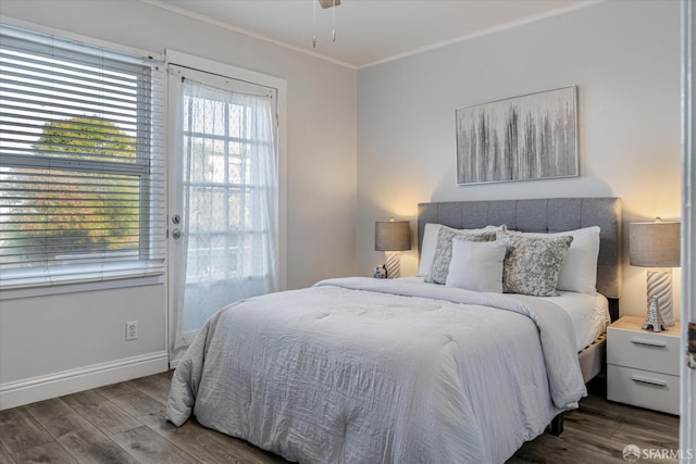 bedroom featuring baseboards, wood finished floors, and crown molding