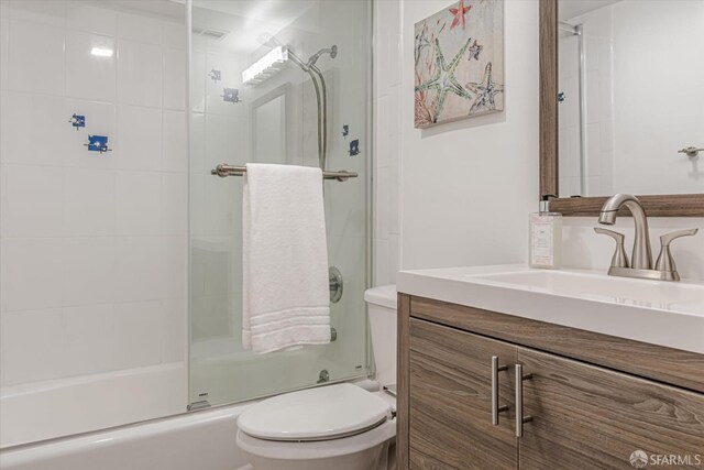 bathroom featuring combined bath / shower with glass door, vanity, and toilet