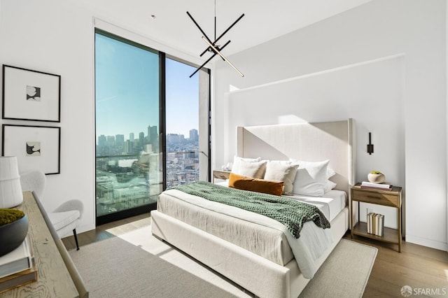 bedroom with floor to ceiling windows, hardwood / wood-style floors, and an inviting chandelier