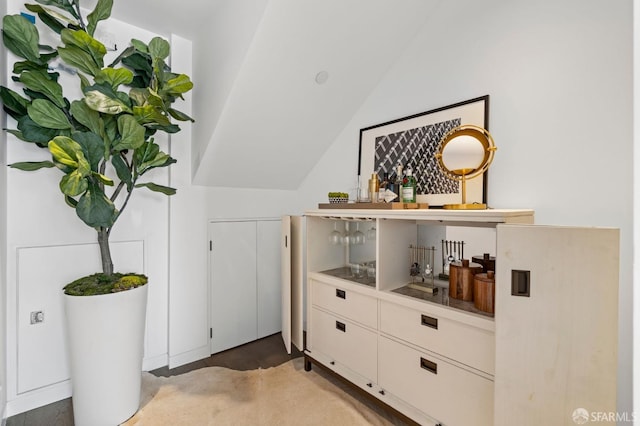 bar featuring lofted ceiling and white cabinetry