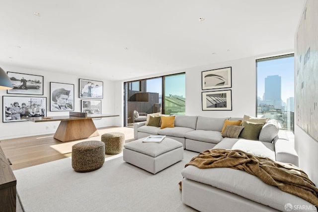 living room with a wealth of natural light, floor to ceiling windows, and light hardwood / wood-style flooring