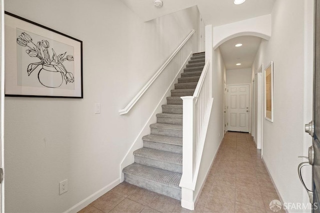 stairs featuring arched walkways, tile patterned floors, recessed lighting, and baseboards