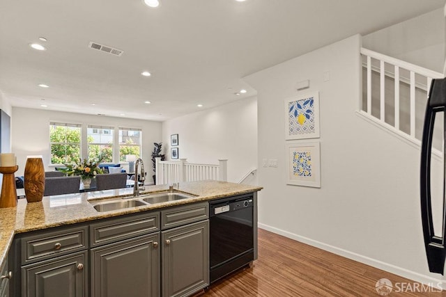 kitchen featuring visible vents, wood finished floors, baseboards, a sink, and dishwasher