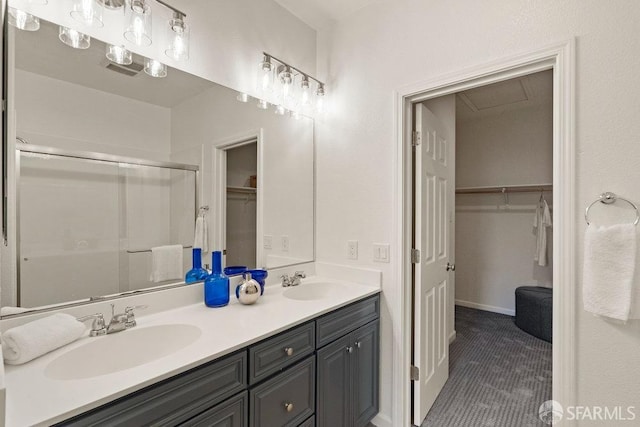 bathroom featuring double vanity, a sink, a walk in closet, and a stall shower