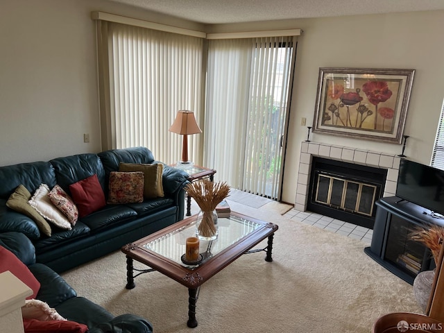 carpeted living room with a tiled fireplace and a textured ceiling