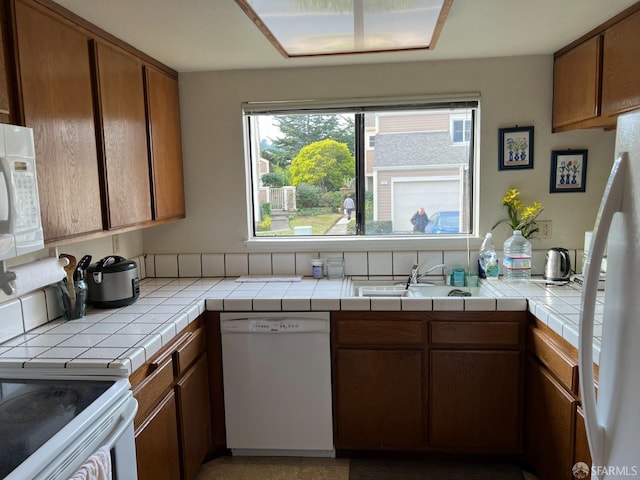 kitchen with sink, white appliances, and tile counters