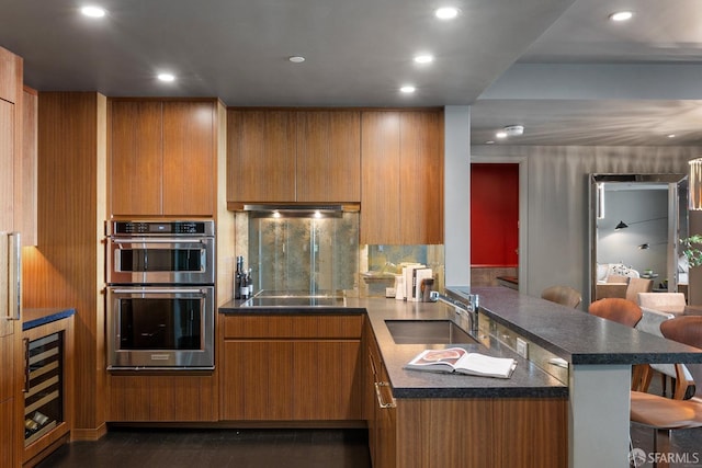 765 Market St Unit 32H, San Francisco, CA 94103 - kitchen featuring a kitchen breakfast bar, dark countertops, a sink, double oven, and a peninsula