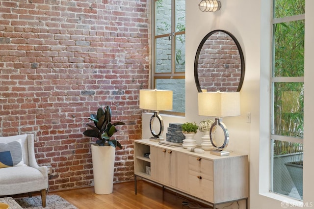 sitting room with hardwood / wood-style floors and brick wall