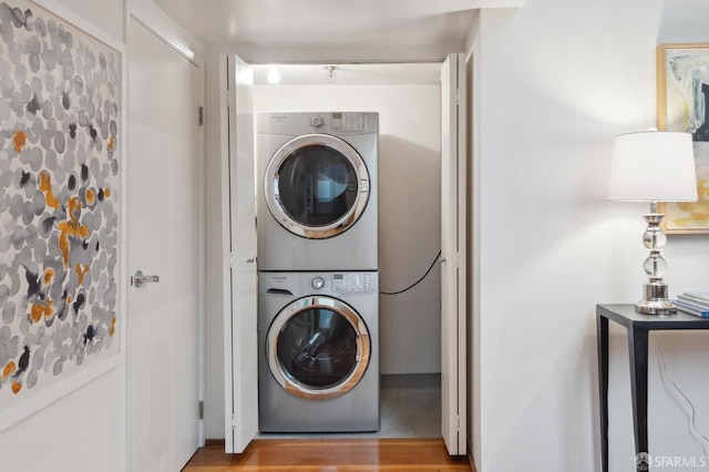 laundry area with hardwood / wood-style floors and stacked washer and clothes dryer