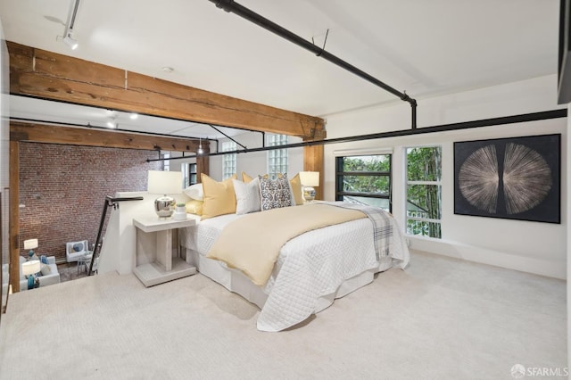 carpeted bedroom with beam ceiling, rail lighting, and brick wall