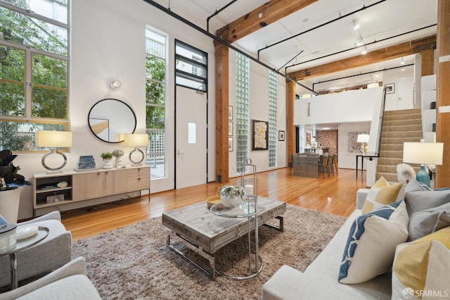 living room with hardwood / wood-style floors, track lighting, and a high ceiling