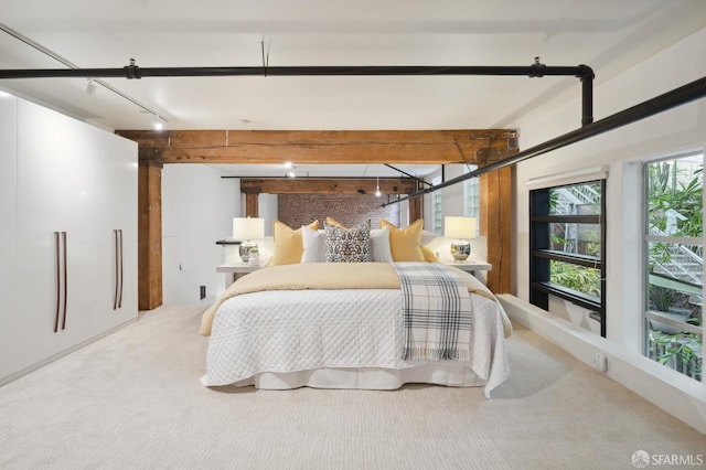 bedroom with carpet flooring, track lighting, and beamed ceiling