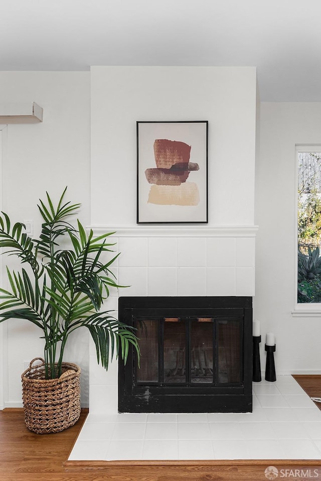 room details featuring a tile fireplace and wood-type flooring