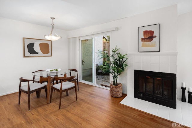 dining space featuring a tiled fireplace and wood-type flooring