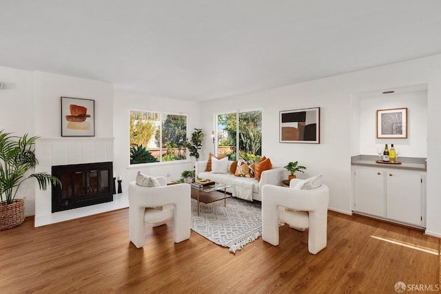 living room featuring a tile fireplace and hardwood / wood-style floors