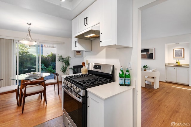 kitchen featuring white cabinets, stainless steel gas stove, light hardwood / wood-style floors, and decorative light fixtures