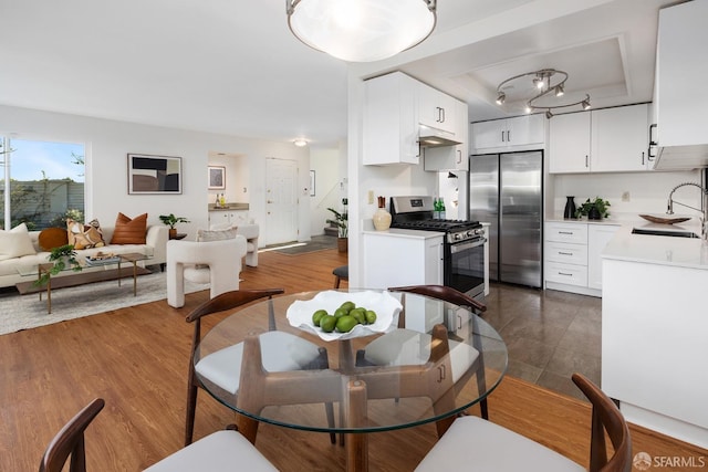 dining area with a raised ceiling, sink, and dark wood-type flooring