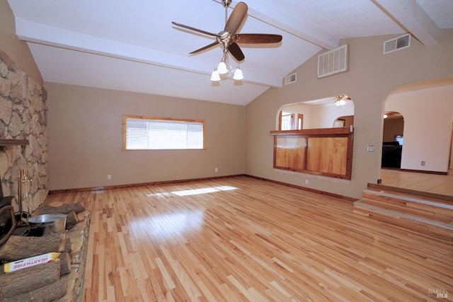 unfurnished living room with light wood-type flooring, a fireplace, ceiling fan, beam ceiling, and high vaulted ceiling