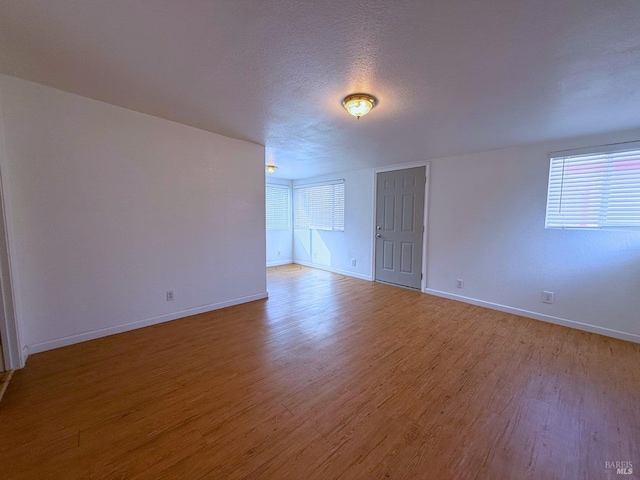 spare room featuring light hardwood / wood-style flooring and a textured ceiling