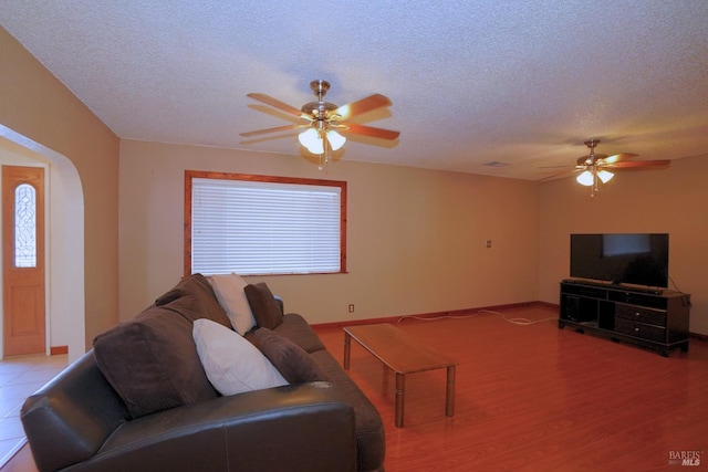 living room with a textured ceiling, light wood-type flooring, and ceiling fan