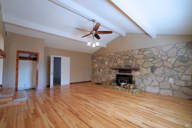 unfurnished living room with lofted ceiling with beams, light hardwood / wood-style floors, a wood stove, and ceiling fan