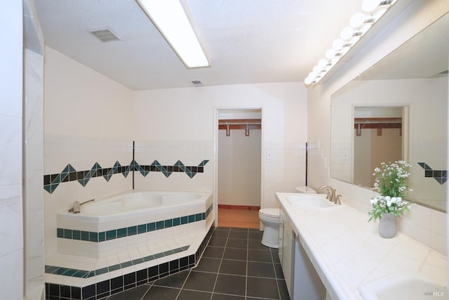 bathroom featuring tile patterned floors, tile walls, toilet, vanity, and tiled tub