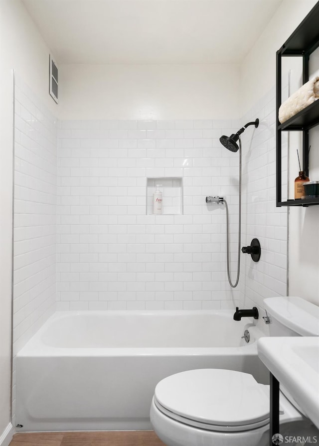 bathroom with toilet and tiled shower / bath combo