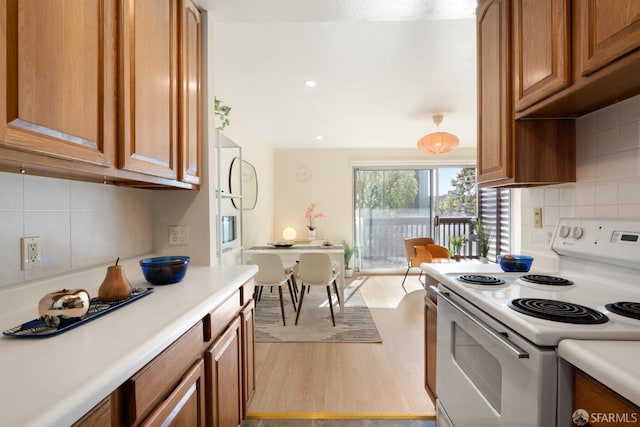 kitchen with light hardwood / wood-style floors, backsplash, and electric range