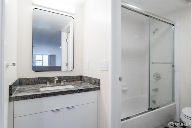 full bath featuring combined bath / shower with glass door, vanity, and toilet