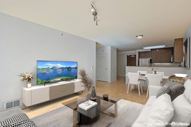 living area featuring light wood-type flooring, visible vents, and track lighting