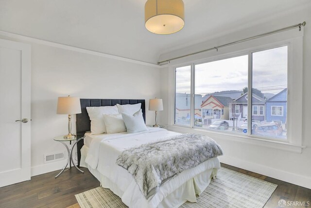 bedroom with dark hardwood / wood-style flooring, vaulted ceiling, and multiple windows