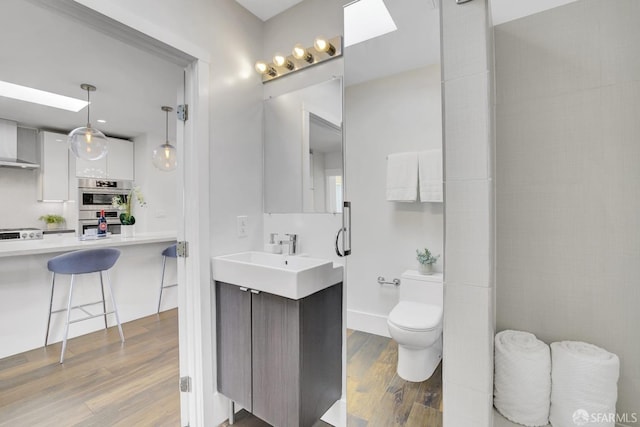 bathroom with backsplash, hardwood / wood-style floors, vanity, and toilet