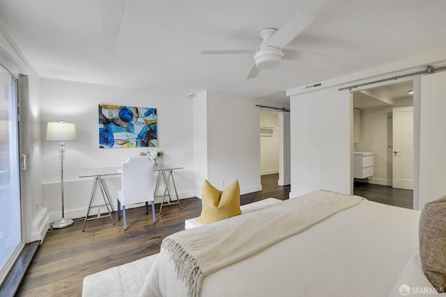 bedroom with ensuite bath, access to outside, ceiling fan, a barn door, and dark hardwood / wood-style floors