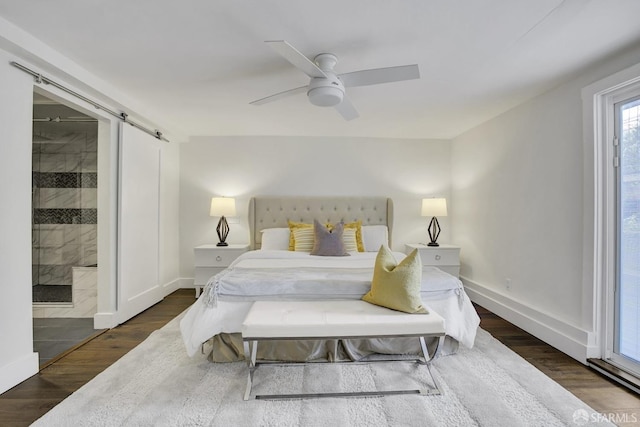 bedroom featuring ceiling fan, a barn door, dark hardwood / wood-style flooring, and ensuite bath