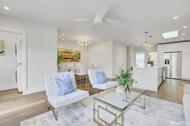 living room featuring sink, a skylight, hardwood / wood-style flooring, ceiling fan, and washer / clothes dryer