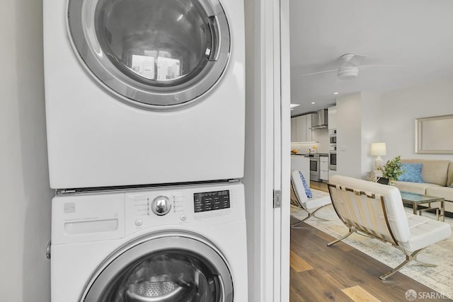 laundry room featuring dark hardwood / wood-style floors, ceiling fan, and stacked washer and dryer