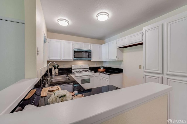 3685 Nutwood Ter Unit 313, Fremont, CA 94536 - kitchen featuring white range with gas cooktop, a sink, white cabinets, and dark countertops