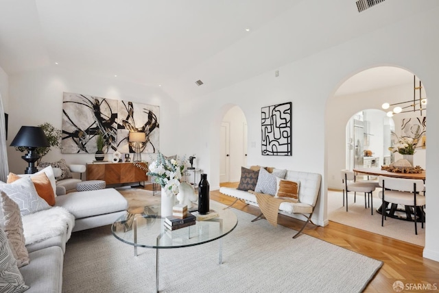 living room with light parquet floors, lofted ceiling, and a notable chandelier