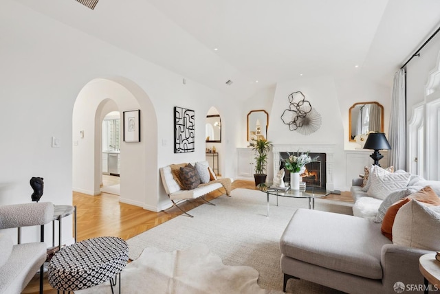 living room featuring lofted ceiling, a high end fireplace, and light wood-type flooring