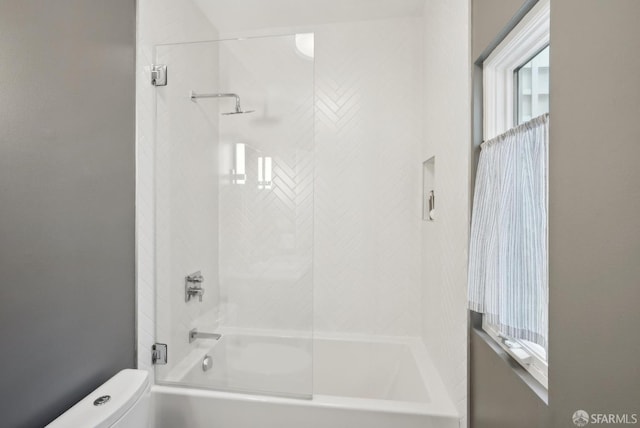 bathroom featuring toilet and tiled shower / bath