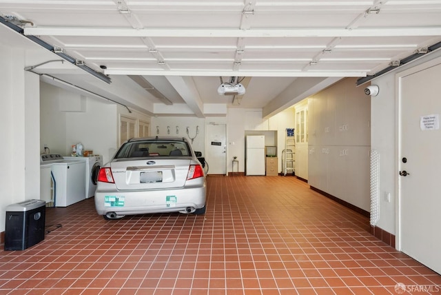 garage featuring white refrigerator, a garage door opener, and washer and dryer