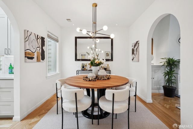 dining area with a chandelier and light parquet flooring