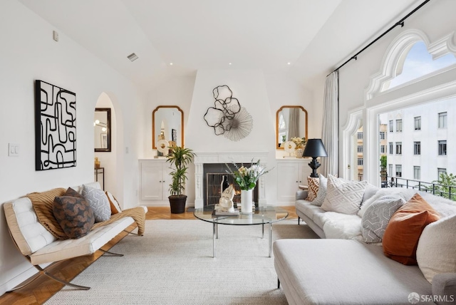 living room featuring light hardwood / wood-style flooring, high vaulted ceiling, and a premium fireplace